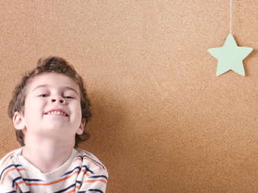 child smiling at camera with a hanging star