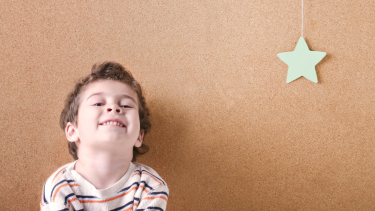 child smiling at camera with a hanging star
