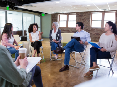 Adults sitting in circle on chairs talking
