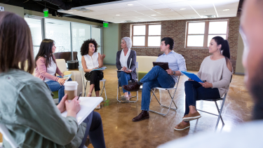 Adults sitting in circle on chairs talking